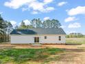 A home's rear exterior features sliding glass doors and simple landscaping against a backdrop of trees at 9550 Stallings Road Rd, Spring Hope, NC 27882