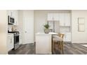 Bright kitchen with white cabinets, stainless steel appliances, and an island with bar stool seating at 1002 Sora Way, Durham, NC 27703