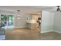 Open-concept living room and kitchen with light gray walls, wood floors, modern lighting, and glass patio doors at 245 Marilyn Cir, Cary, NC 27513