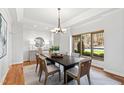 Bright dining room featuring hardwood floors, a modern chandelier, and a large window with beautiful outside views at 301 Stone Currie Dr, Hillsborough, NC 27278