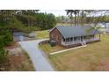 Single-story brick home with welcoming front porch, storage shed, and gravel driveway in wooded setting at 3026 Shoeheel Rd, Kenly, NC 27542