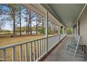 Inviting front porch featuring rocking chairs, overlooking a spacious lawn and serene wooded landscape at 3026 Shoeheel Rd, Kenly, NC 27542