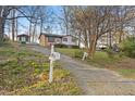 Single-story home on a sloping lot with mature trees, accessed by a paved driveway at 3416 North Ridge Dr, Sanford, NC 27330