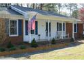 Close up view of the exterior elevation of the charming home, featuring an american flag and a bench at 5520 Mccormick Rd, Durham, NC 27713