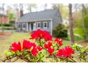 Close-up of bright red azaleas in front of a gray home, accentuating the natural beauty of the property at 5608 Ventura Dr, Durham, NC 27712