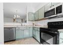 Modern kitchen features stainless steel appliances, tile floors, and sage-colored cabinets at 5980 Osprey Cove Dr, Raleigh, NC 27604