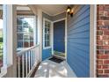 Close-up of a blue front door with sidelight windows and a 'welcome' mat on a covered porch at 6 Preakness Dr, Durham, NC 27713