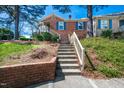 Brick home entrance with stairs leading to the door, accented by blue shutters and lush greenery at 6 Preakness Dr, Durham, NC 27713