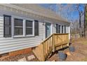 Close-up of the home's entrance showcasing a blue door, wooden deck, and well-kept landscaping with potted plants at 612 Miller Rd, Hillsborough, NC 27278