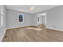 An empty living room with gray walls and hardwood floors, illuminated by natural light from the windows at 612 Miller Rd, Hillsborough, NC 27278