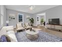 Staged living room with modern furniture and decor, featuring a blue rug and view into the dining area at 612 Miller Rd, Hillsborough, NC 27278