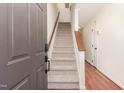 Inviting entryway featuring a staircase with carpeted steps and a wooden handrail in a brightly lit interior at 6734 Chauncey Dr, Raleigh, NC 27615