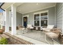 Inviting covered porch with brick base, cozy seating, and a decorative wreath on the front door at 705 Marshall Farm St, Wake Forest, NC 27587