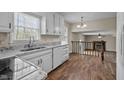 Bright kitchen with white cabinets, granite countertops, a stainless steel sink, and hardwood floors with a view into living room at 1108 Medlin Dr, Cary, NC 27511