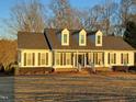 Beautiful white home featuring dormer windows and dark shutters, nestled among mature trees at 117 Linwood Ln, Clayton, NC 27527