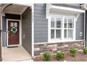 Close-up of a front door adorned with a wreath, complemented by a window and stone accents at 1243 White Flint Cir, Durham, NC 27703