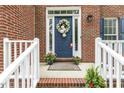 Charming front porch with white railing, red brick steps and a welcoming blue door with floral decorations at 2310 Nutting Ln, Apex, NC 27523