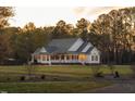 Single-story home featuring a wide porch with a white railing, set against a backdrop of mature trees at 2905 Glendale Rd, Kenly, NC 27542
