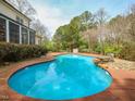 Refreshing backyard pool featuring brick patio and lush greenery at 2932 Candlehurst Ln, Raleigh, NC 27616