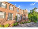 Brick townhomes feature well-kept front gardens, enhanced by lush green foliage and blue skies at 4 Scottish Ln, Durham, NC 27707