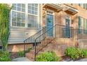 Inviting front porch with brick steps, black iron railing, and a teal-painted front door with wreath at 4 Scottish Ln, Durham, NC 27707