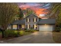 Charming two-story home with gray siding, black shutters, attached garage and landscaped front yard at sunset at 516 Edinburgh Dr, Burlington, NC 27215