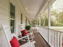 Cozy front porch featuring rocking chairs with red pillows, plants, and a view of the surrounding nature at 5209 Rivington Rd, Fuquay Varina, NC 27526