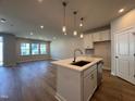 Open-concept kitchen with island, stainless appliances, and hardwood floors open to large living area at 609 Callan View Ave, Wake Forest, NC 27587