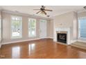 Spacious living room featuring hardwood floors, a fireplace, a ceiling fan, and natural light from large windows at 7819 Acc Blvd, Raleigh, NC 27612