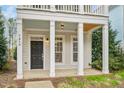 Detailed view of the front porch with white columns and a black front door with sidelight windows at 7819 Acc Blvd, Raleigh, NC 27612