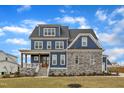 Charming blue two-story home featuring stone accents, a covered porch, manicured lawn, and inviting curb appeal at 1160 Duke Farm Dr, Wake Forest, NC 27587