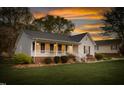 Charming single story home with a well-maintained lawn, inviting porch, and attractive landscaping at sunset at 124 Holly Ridge Ln, Mebane, NC 27302