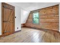 Bright bedroom with wood-paneled walls and ceiling, showcasing a rustic door and original hardwood floors at 207 High House Rd, Cary, NC 27513