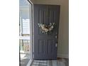 Inviting gray front door with a modern wreath, opening to a glimpse of the home's interior at 2915 Cox Mill Rd, Sanford, NC 27332