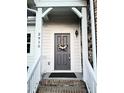 Stylish gray front door adorned with a floral wreath, complemented by white trim and brick accents at 2915 Cox Mill Rd, Sanford, NC 27332