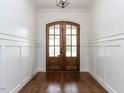 Elegant entryway with a double wooden door, gleaming hardwood floors, and classic wainscoting at 3908 Sage Ct, Wake Forest, NC 27587