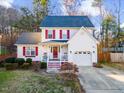 Attractive two-story home featuring red shutters, a cozy front porch, attached garage, and well-maintained lawn at 409 Machost Dr, Garner, NC 27529