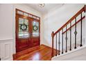 Elegant foyer with gleaming hardwood floors, a staircase with wrought iron railings, and a double-door entrance at 44 Grandwood Cir, Durham, NC 27712