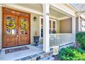 Inviting covered front porch features a double-door entrance, stylish lighting, and a cozy seating area at 44 Grandwood Cir, Durham, NC 27712