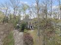 An aerial view captures a brick home nestled amongst mature trees, with a neatly manicured lawn and driveway at 721 Blenheim Dr, Raleigh, NC 27612