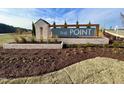 Community sign reading 'The Point' with stone accents, landscaping, and a bright blue sky at 1173 Solace Way, Rolesville, NC 27571