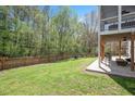 Spacious backyard featuring a lush lawn, wooden fence, and a covered patio area at 118 Benedum Pl, Cary, NC 27518