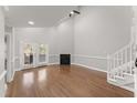 Airy living room featuring a fireplace, hardwood floors, staircase, and a glass door leading to the outdoors at 1426 Quarter Pt, Raleigh, NC 27615