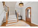 Elegant foyer with hardwood floors, a grand staircase, eye-catching light fixture, and decorative front door at 1629 Montvale Grant Way, Cary, NC 27519