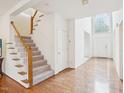 Bright foyer with hardwood floors, a staircase with carpeted steps, and natural light from the large window at 1903 Yellowwood Ln, Durham, NC 27712