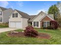 A view of the front yard showing mature landscaping, a two-car garage, and a well-maintained lawn at 203 Grassy Point Rd, Apex, NC 27502