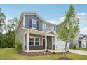 Charming two-story home featuring a two-car garage, red door, and a cozy front porch at 2202 Cherry Creek Rd, Haw River, NC 27258