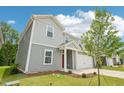 Charming two-story home featuring gray siding, a red front door, an attached garage, and landscaped front yard at 2206 Cherry Creek Rd, Haw River, NC 27258