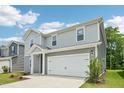 Charming two-story home featuring gray siding, a red front door, an attached garage, and landscaped front yard at 2206 Cherry Creek Rd, Haw River, NC 27258