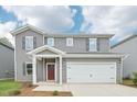 Two-story home featuring gray siding, a two-car garage and a covered front porch at 2210 Cherry Creek Rd, Haw River, NC 27258